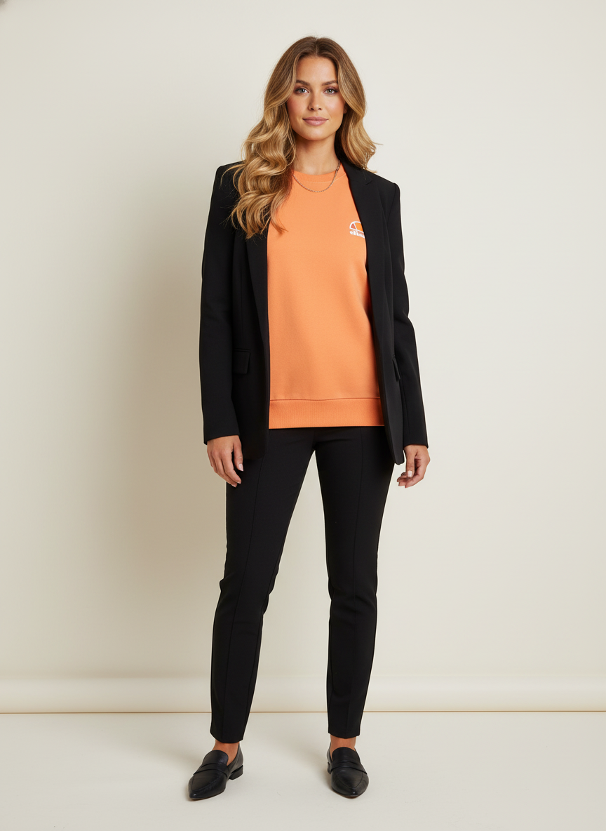 Model i orange sweatshirt med klassisk crewneck – styling: blazer chic