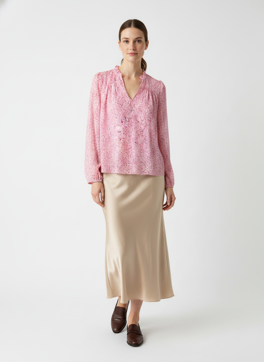 Model i lyserød bluse med konfetti-print og flæsekrave – step skirt loafers