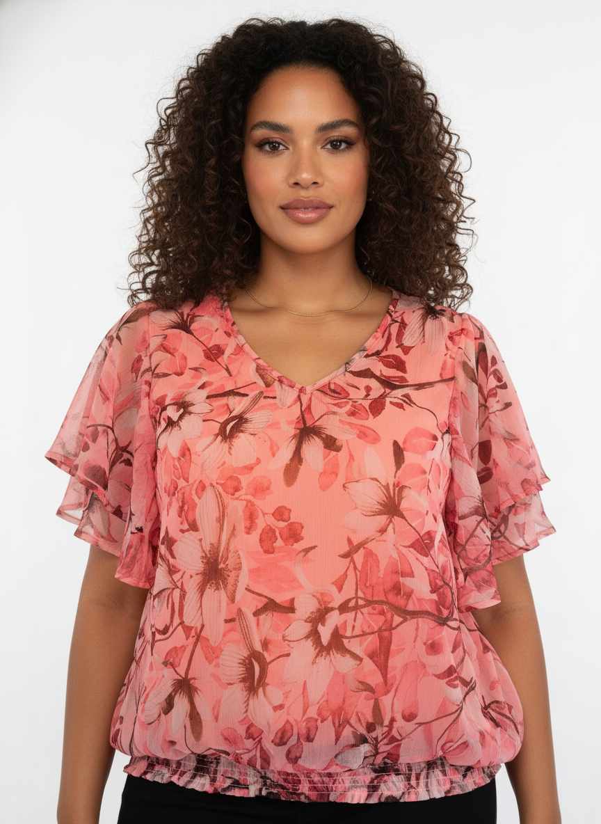 Model i koralpink chiffon-bluse med blomster-print og flæseærmer – detail